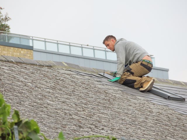A roofer inspecting shingle damage during a roof repair Homosassa job on a residential property